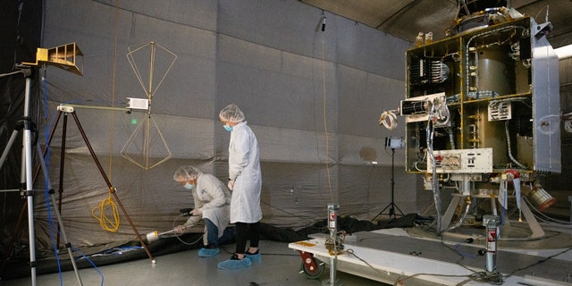 The DART spacecraft undergoes electromagnetic interference testing; from left, Alan Busbey performs measurements with Jackie Kilheffer overseeing the process.
