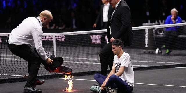 A protester lights a fire on the court on day one of the Laver Cup at the O2 Arena, London Friday, Sept. 23, 2022. 