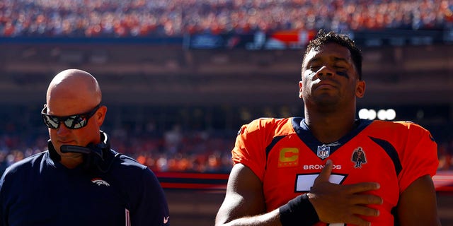 Head coach Nathaniel Hackett and Russell Wilson #3 of the Denver Broncos take a moment during the national anthem prior to playing the Houston Texans at Empower Field At Mile High on Sept. 18, 2022 in Denver, Colorado.