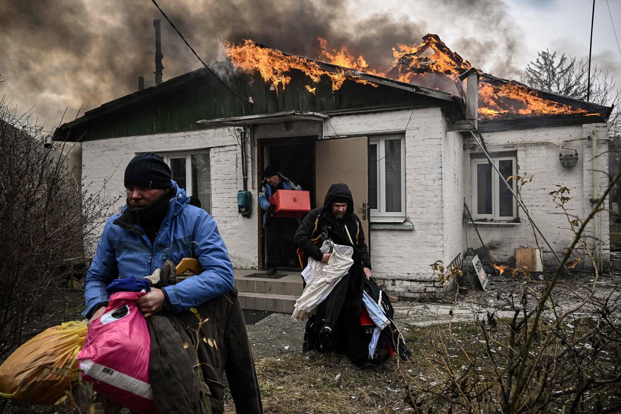 People remove personal belongings from a burning house after shelling in Irpin on March 4.