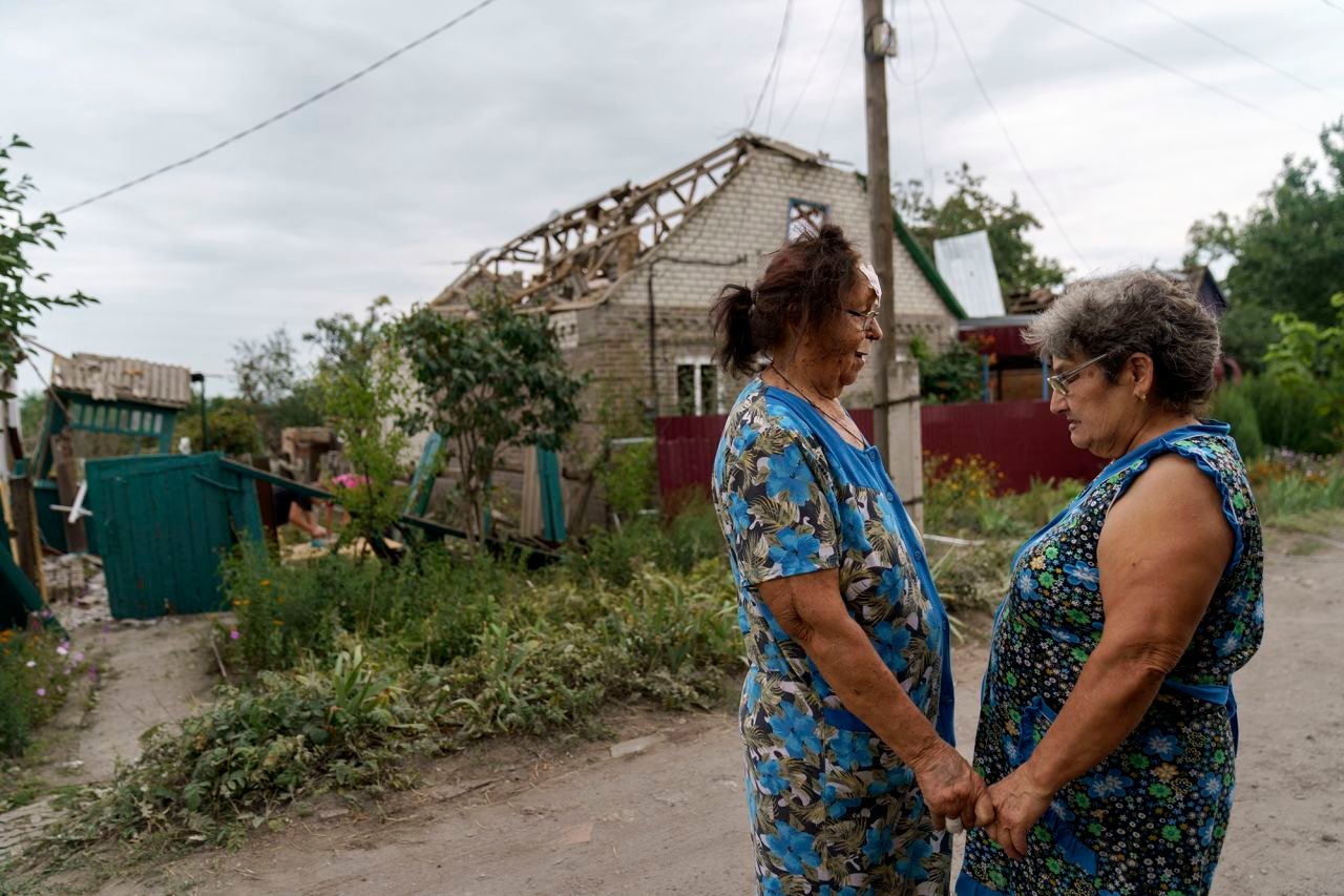 Valentyna Kondratieva, 75, left, is comforted by a neighbor as they stand outside her damaged home, in Kramatorsk, Ukraine, on August 13, after a rocket attack.