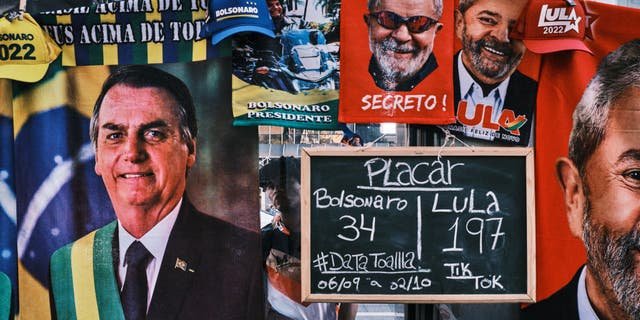 SAO PAULO, BRAZIL - SEPTEMBER 23: A man stands by a street stall selling towels of presidential candidates Luis Inacio Lula da Silva and Jair Bolsonaro at Paulista Avenue on September 23, 2022, in Sao Paulo, Brazil. The stall displays a sign with the number of towels of each candidate sold so far. Brazilians will go to polls on October 30 in the next round of the country's polarized presidential election. (Photo by Gustavo Minas/Getty Images)