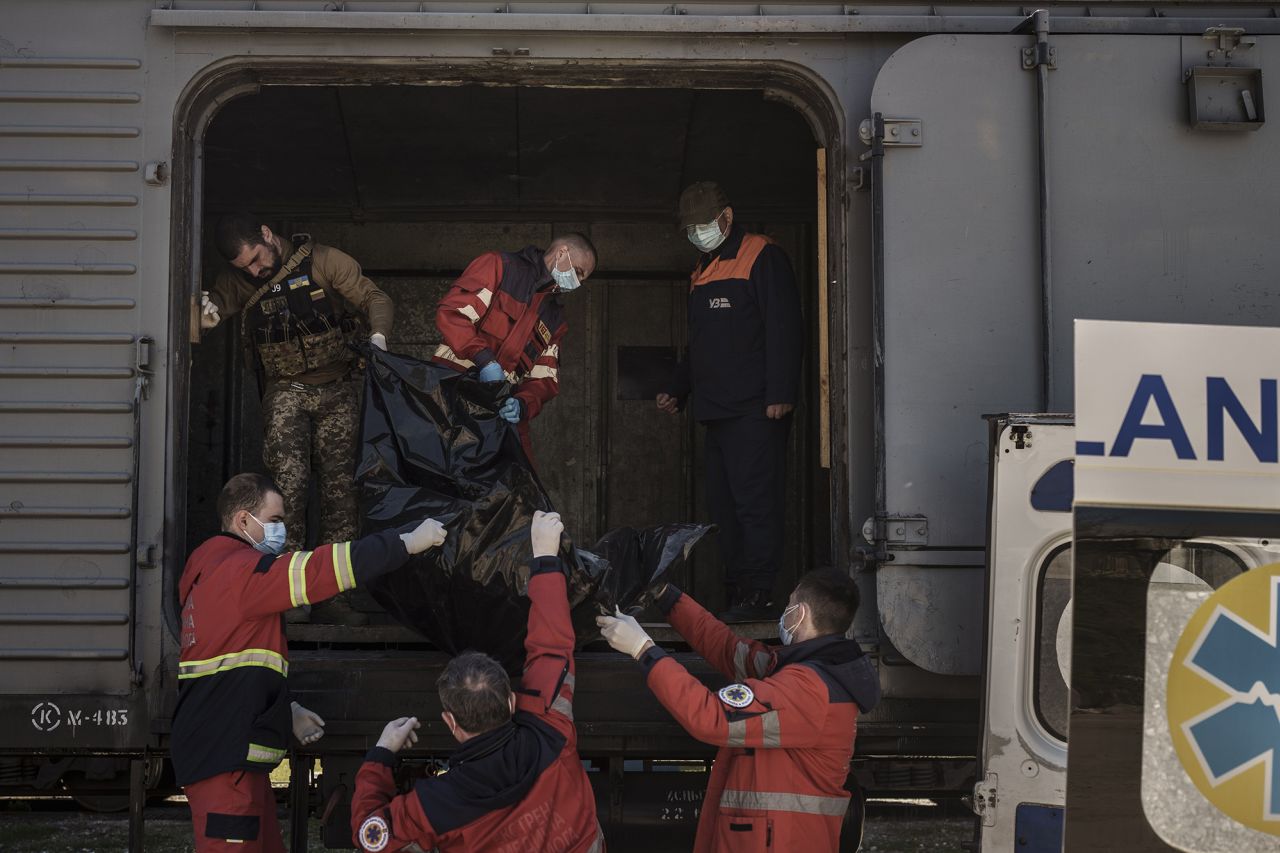 Ukrainian serviceman and emergency workers carry the body of a Russian soldier into a refrigerated train in Kharkiv on May 5. The bodies of more than 40 Russian soldiers were being stored in the refrigerated car. 