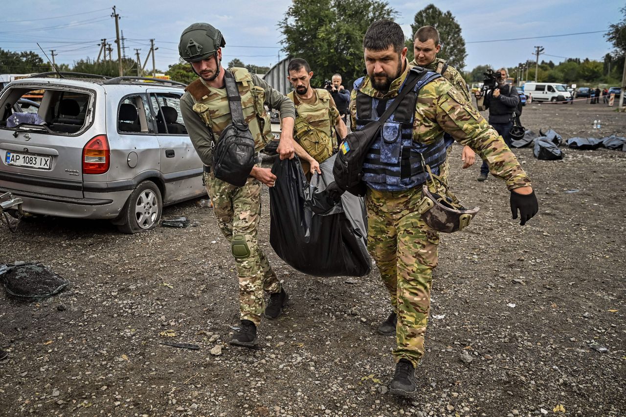 Ukrainian servicemen carry a body bag at the site of a missile <a href=