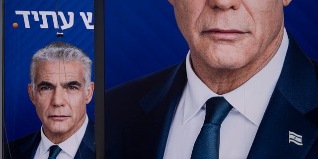 Workers hang an election campaign billboard for the Yesh Atid party, showing Israeli Prime Minister and the head of the party Yair Lapid, in Ramat Hasharon, Israel, Oct. 23, 2022. Israel is heading into its fifth election in under four years Nov. 1.