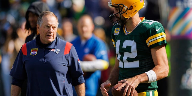 Green Bay Packers quarterback Aaron Rodgers, #12, talks with New England Patriots head coach Bill Belichick during warmups prior to the game at Lambeau Field Oct. 2, 2022 in Green Bay, Wisconsin.