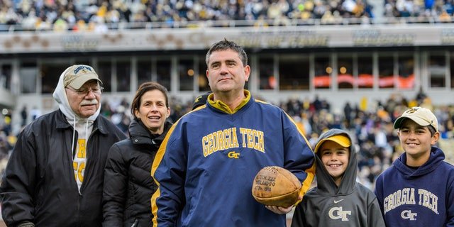 Georgia Tech beat Cumberland College 222-0 Oct. 7, 1916. Georgia Tech alumnus Ryan Schneider and his family are shown here. Schneider purchased a ball used in the game at auction in 2014 and donated it to the university. The ball, showing the score, is on display in the Edge Center, Georgia Tech athletics’ headquarters.