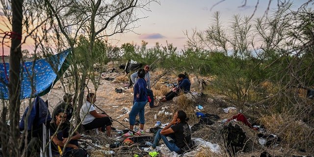 (file photo) Migrants rest after crossing the Rio Grande River as they wait to get apprehended by Border Patrol agents as National Guard agents sit on a car across the street (out of frame), in Eagle Pass, Texas, at the border with Mexico on June 30, 2022.