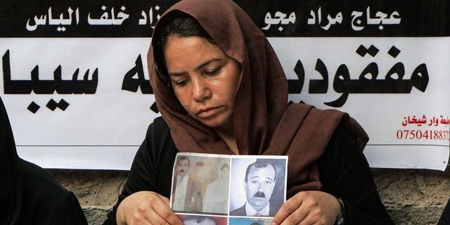 A member of Iraq's Yazidi community holds photos of victims of the August 2014 massacre carried out by Islamic State militants, during a commemoration of the eighth anniversary of the event at the Temple of Lalish, near the Iraqi Kurdish city of Dohuk on Aug. 2, 2022.
