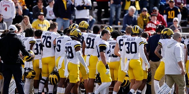 Michigan Wolverines players and coaches watch as medical attention is given to running backs coach Mike Hart after he collapsed on the sideline during a college football game against the Indiana Hoosiers on Oct. 8, 2022 at Memorial Stadium in Bloomington, Indiana.