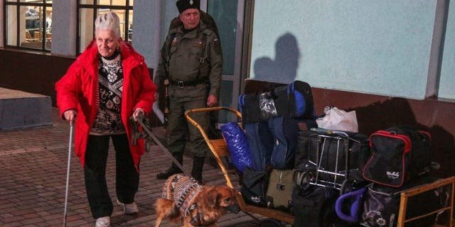 A woman arrived from Kherson leads her dog along a platform for further evacuation into the depths of Russia at the Dzhankoi's railway station in Crimea on Oct. 21, 2022.