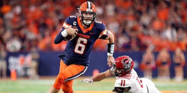 Garrett Shrader, #6 of the Syracuse Orange, runs the ball as Payton Wilson, #11 of the North Carolina State Wolfpack, attempts to tackle Shrader during the third quarter at JMA Wireless Dome on Oct. 15, 2022 in Syracuse, New York.