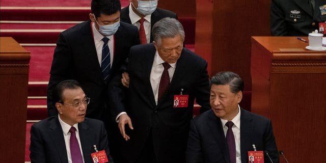 BEIJING, CHINA - OCTOBER 22: Chinese President Xi Jinping and Premier Li Keqiang, left, look on as former President Hu Jintao, centre, speaks to Xi as he is helped to leave early from the closing session of the 20th National Congress of the Communist Party of China, at The Great Hall of People on October 22, 2022 in Beijing, China's Communist Party Congress is concluding today with incumbent President Xi Jinping expected to seal a third term in power.