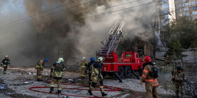 Firefighters help a local woman evacuate from a residential building destroyed by a Russian drone strike, which local authorities consider to be Iranian-made unmanned aerial vehicles (UAVs) Shahed-136, amid Russia's attack on Ukraine, in Kyiv, Ukraine October 17, 2022.