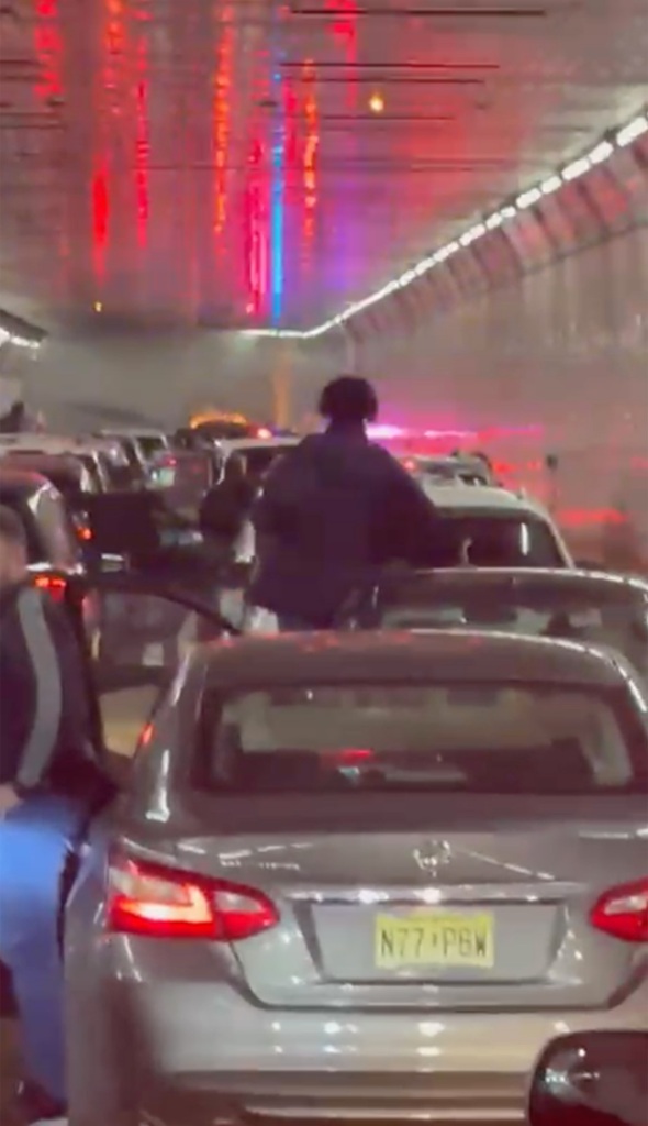 People step out of their cars parked inside the Holland Tunnel to observe a car on fire in the tunnel.