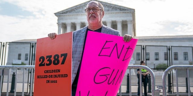 A protester holds signs calling for an end to gun violence in front of the Supreme Court on June 8, 2022, in Washington, DC.