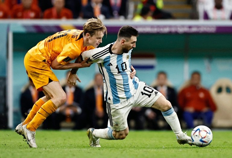Messing kicking the ball as de Jong is behind him, grabbing on to his right arm