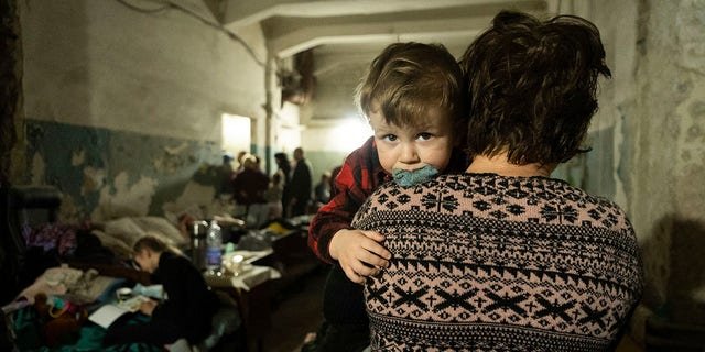 A woman holds a child in an improvised bomb shelter in Mariupol, Ukraine, Monday, March 7, 2022.