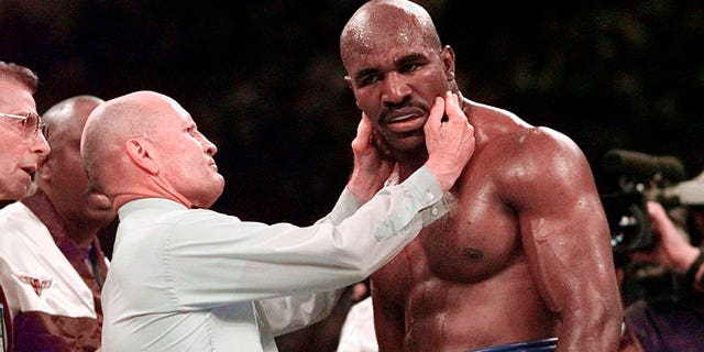 Evander Holyfield has his right ear checked by referee Mills Lane after he was bit on the ear by Mike Tyson during the third round of their WBA heavyweight boxing match June 28, 1997, in Las Vegas.