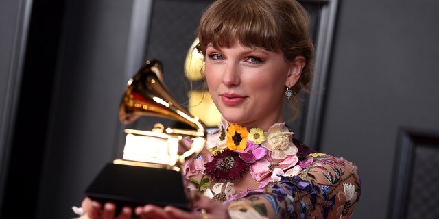 Taylor Swift poses in the press room with the award for album of the year for "Folklore" at the 63rd annual Grammy Awards at the Los Angeles Convention Center on Sunday, March 14, 2021.