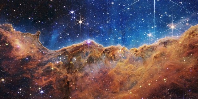 What looks much like craggy mountains on a moonlit evening is actually the edge of a nearby, young, star-forming region NGC 3324 in the Carina Nebula. Captured in infrared light by the Near-Infrared Camera (NIRCam) on NASA’s James Webb Space Telescope, this image reveals previously obscured areas of star birth.
