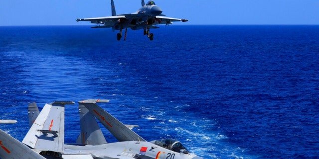 In this photo released Dec. 31, 2021, by Xinhua News Agency, an undated photo shows a carrier-based J-15 fighter jet preparing to land on the Chinese navy's Liaoning aircraft-carrier during open-sea combat training.