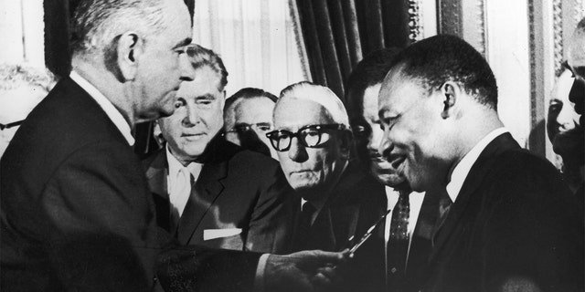 President Lyndon B. Johnson hands a pen to the Rev. Martin Luther King Jr. during the signing of the Voting Rights Act in Washington, D.C., Aug. 6, 1965.