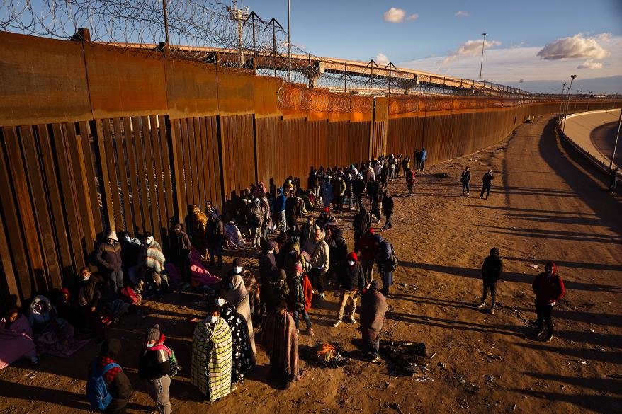 Migrants line up to be transported by U.S. Customs and Border Protection officers after they crossed the U.S.-Mexico Border at the Rio Grande River from Ciudad Juarez, Mexico to El Paso, Texas, on Saturday, December 31, 2022