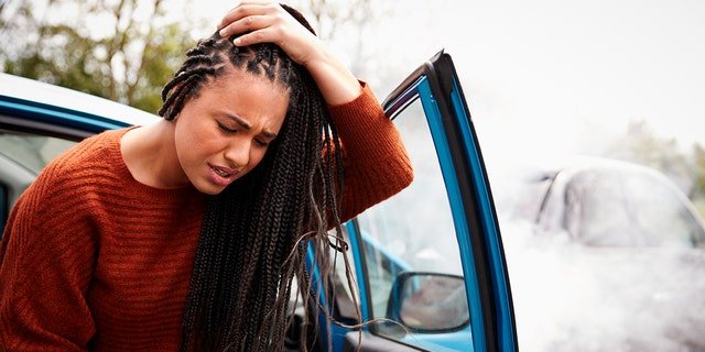 A female motorist with a head injury exits her car after a crash.