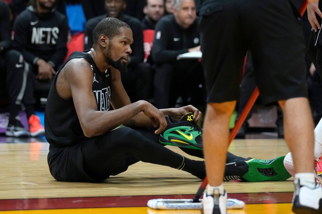 Brooklyn Nets forward Kevin Durant puts his shoe back on after a play during the second half of an NBA basketball game against the Miami Heat, Sunday, Jan. 8, 2023, in Miami.