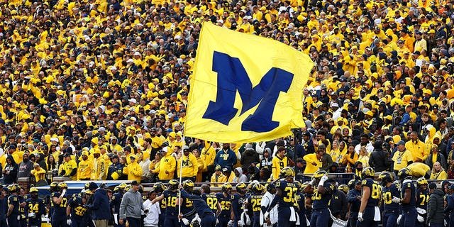 A cheerleader runs a Michigan Wolverines flag up the field after a touchdown during a game against the Penn State Nittany Lions at Michigan Stadium on October 15, 2022, in Ann Arbor, Michigan.