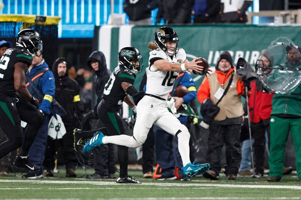Trevor Lawrence #16 of the Jacksonville Jaguars runs with the ball against Michael Carter II #30 of the New York Jets during an NFL football game between the New York Jets and the Jacksonville Jaguars at MetLife Stadium on December 22, 2022.