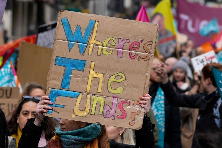 Striking teachers show posters during a protest march in London, Wednesday, Feb. 1, 2023. Thousands of schools in the U.K. are closing some or all of their classrooms, train services will be paralyzed and delays are expected at airports Wednesday in what's shaping up to be the biggest day of industrial action Britain has seen in more than a decade, as unions step up pressure on the government to demand better pay amid a cost-of-living crisis.(AP Photo/Alastair Grant)