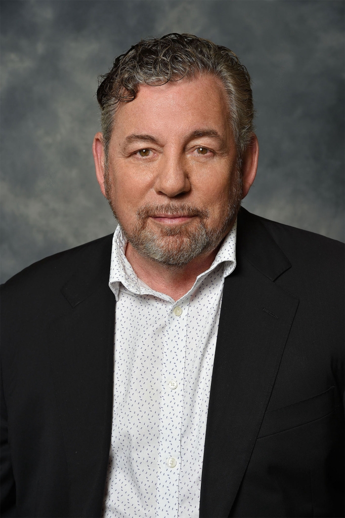 Dolan with black jacket and white shirt with a grey background