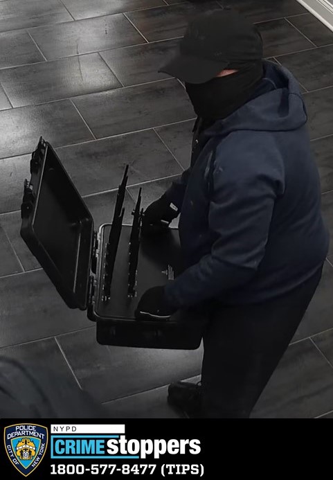 One of the suspects is shown carrying a box as he enters the store. 